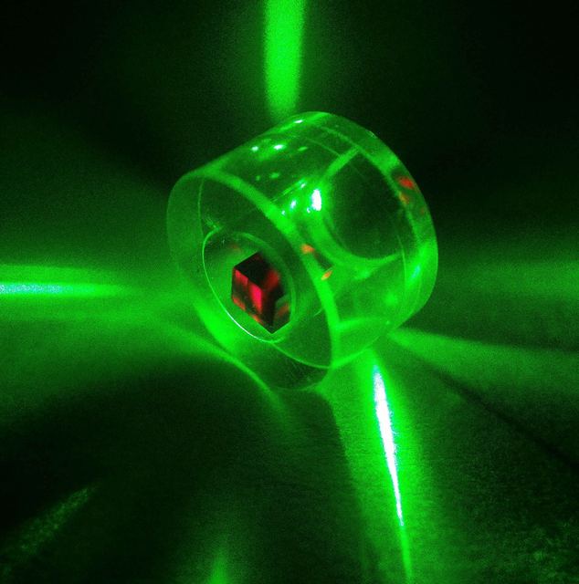 A diamond sample inside a sapphire microwave resonator, illuminated by green pump laser light