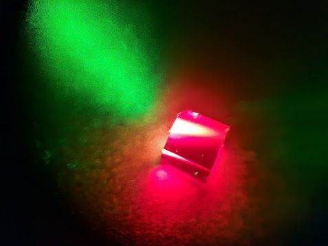 Close-up of a diamond sample fluorescing red under green laser excitation